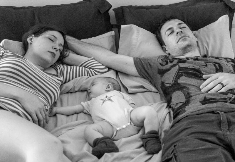 UN couple se reposant avec leur bébé sur un lit